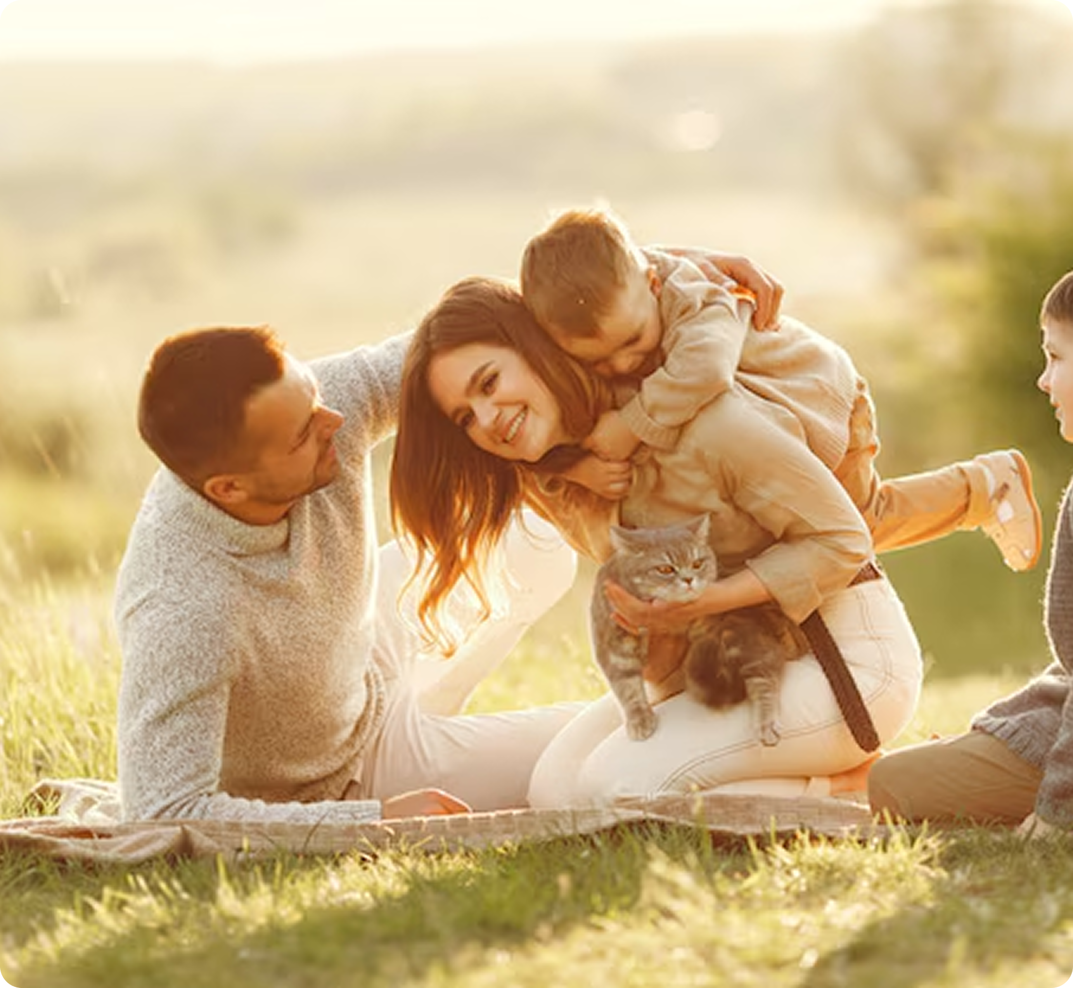 Family of four with a cat sitting on a blanket in a park