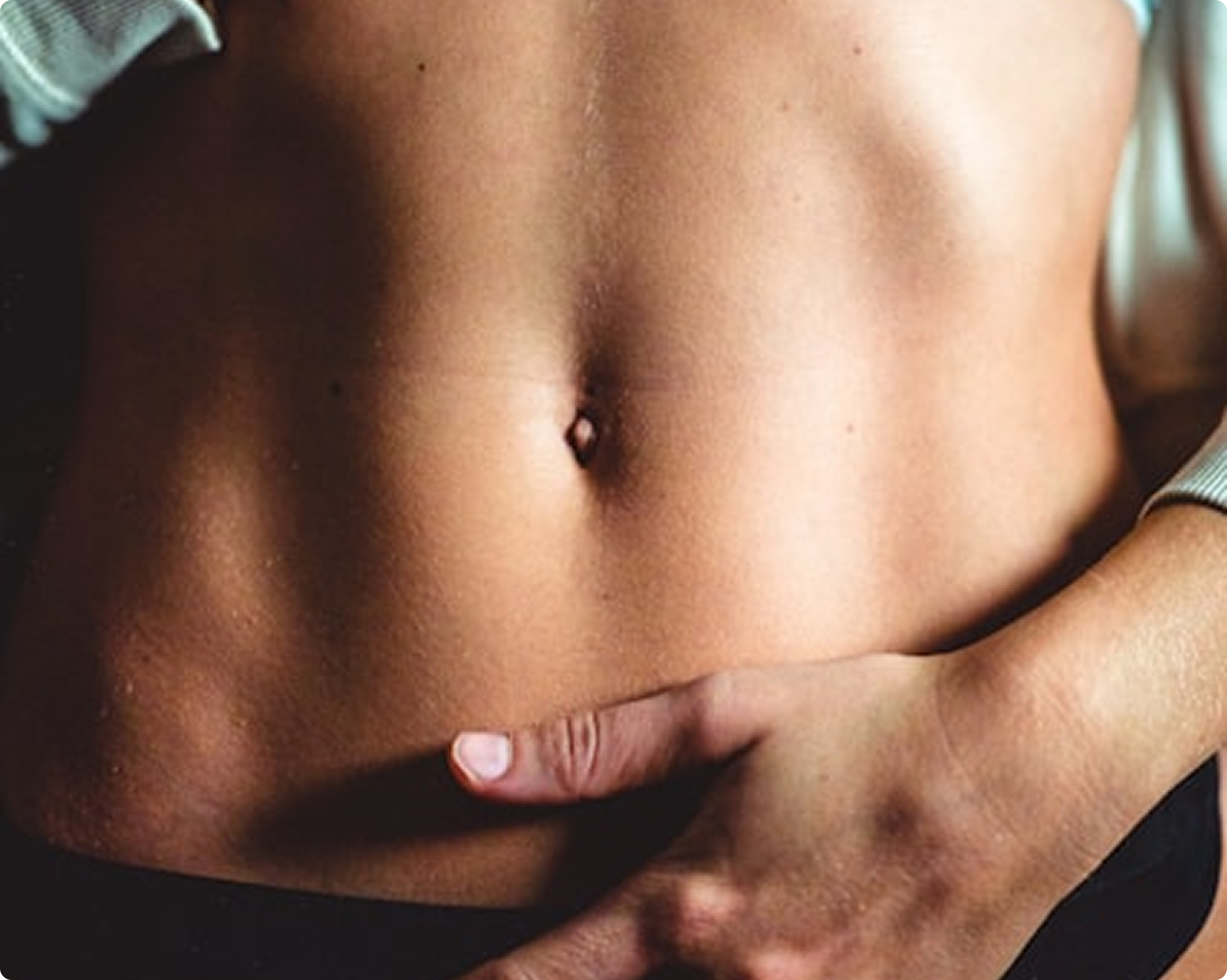 Close-up of a person's torso with a hand pointing to the belly button.