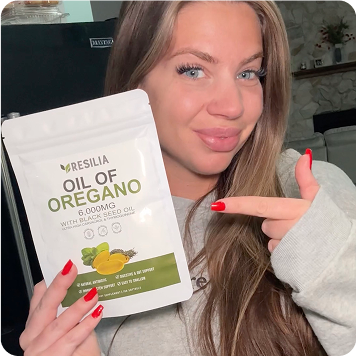 Woman holding a Resilia Oil of Oregano package in front of a refrigerator.