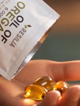 Golden oregano oil softgels in her hand