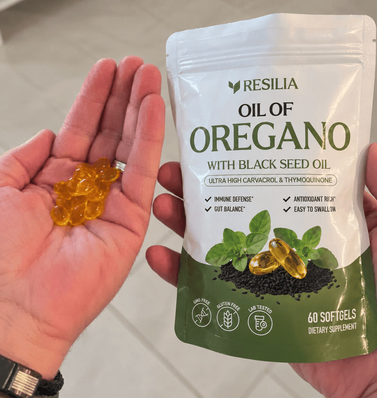 Golden Resilia softgels in a hand beside the pouch