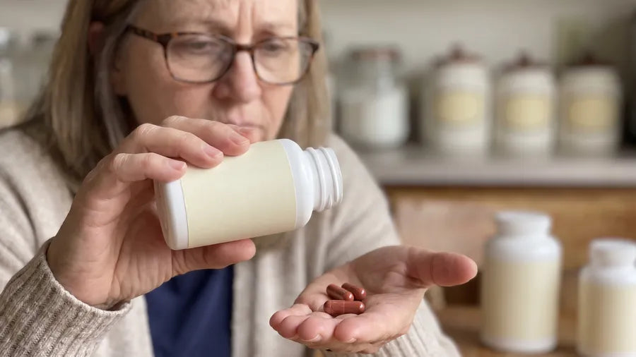 Donna holds a white capsule bottle turned to the back label