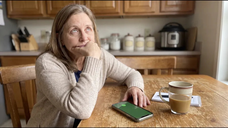 Donna waiting on hold at her kitchen table, phone on speaker