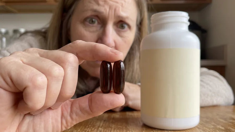 Donna holds two huge dark softgels between her fingers