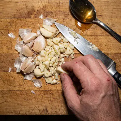 Crushed raw garlic on a cutting board with honey