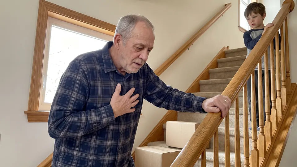 Ron stopped halfway up the stairs holding the rail, hand on his chest, while his grandson waits at the top