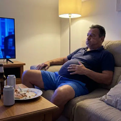 The same man slumped on the couch after dinner with a hand on his full, tight stomach