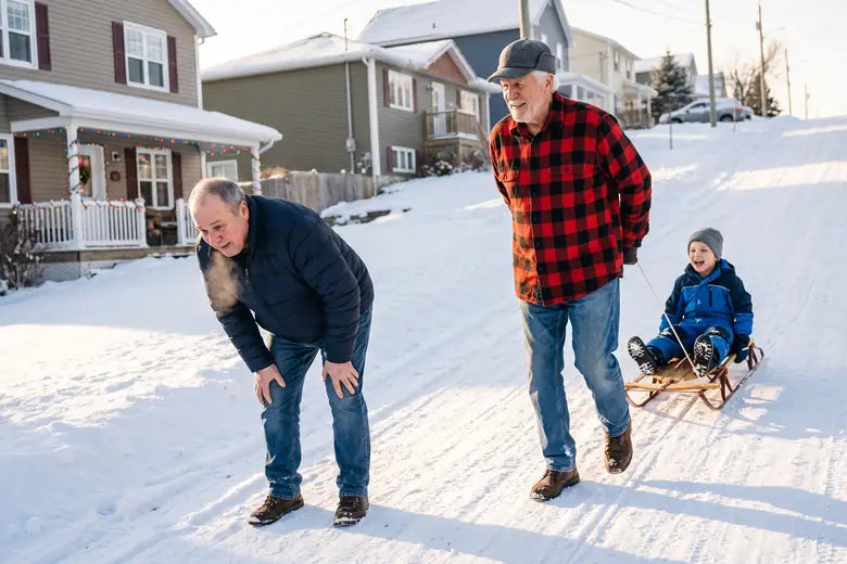 Frank, 74, pulling his grandson's sled up a snowy hill while Mike, 58, stops behind him with his hands on his knees