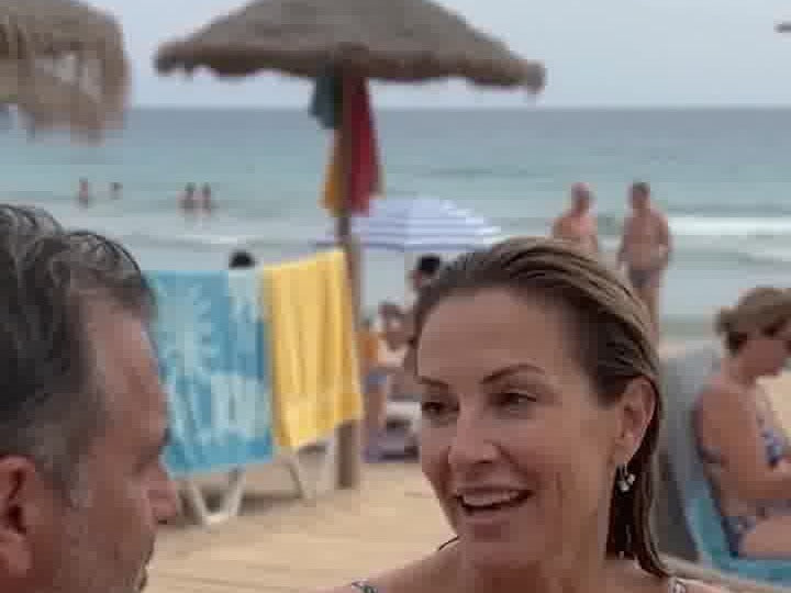A smiling woman chats with a man at a beach bar